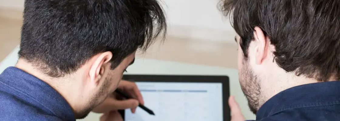 dois homens analisando indicadores em um tablet representando a ncm